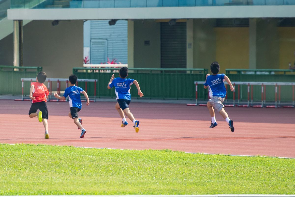 グラウンドのトラックを走る小学生の子どもたち