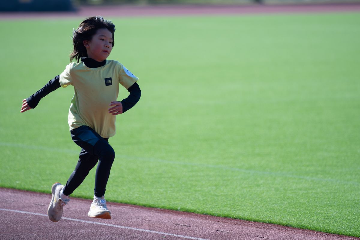 陸上競技場のトラックを全力で走る小学生